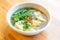 Top view of Wanton soup with morning glory and deep fried garlic in bio paper bowl on wooden background
