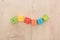 Top view of wavy autism lettering made of multicolored cubes on wooden table.