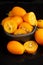 Top view of wet and cut kumquats, in dark bowl, selective focus, black background,