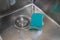 Top view of wet stainless sink with scrub sponge and foam in kitchen, above view.