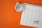 Top view of white analog clock, red pushpin, red circle and pay day text marked the last day of month on orange background