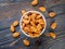 Top view of white bowl with a handful of almond, nuts on a wooden dark background.