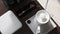 Top view of the white coffeemaker with the cutlery on the wooden surface, close-up