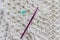 Top view of a white cotton blanket being crocheted, green stitch marker and a 5 mm purple metallic crochet hook