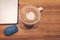 Top view, a white cup hot capuccino with white heart mug on top, a computer labtop and blue mouse on brown wooden table