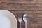 Top view of White dish and fork and spoon cutlery  on a wooden background