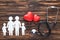 top view of white figures of family holding hands, red hearts symbols and stethoscope on wooden