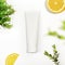 Top view of white plastic tube with lemon and green plant. Unbranded tube for cream, scrub, lotion or serum. Mockup style, copy