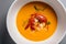 Top view of a white porcelain bowl filled with rich and creamy lobster bisque soup, garnished with a lobster claw