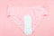 Top view white sanitary napkin and pink underpants on pink background