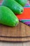 Top view of whole green avocados, with selective focus, on wooden table and red ethnic cloth