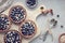 Top view on wholegrain blueberry tarts with vanilla cream on light textured board