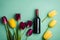 Top view of wine bottle, yellow and red tulips on pastel blue background. Flat lay style