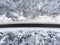 Top view at wintry slippery highway passing through snow covered coniferous forest in mountains