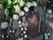 Top view of witch grimoire book, runes and white flowers on planks outside in the garden