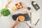 Top view of woman chef breaking an egg into the wood bowl. Female chef whisking eggs in wood bowl on white table