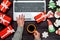 Top view of woman hand holding cup of hot coffee and typing on open laptop keyboard on table with Cristmas decorations.