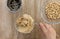 Top view of woman hand holding knife with homemade peanut butter made in grinder on the wooden background