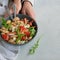 Top view of woman hand holding ready to eat beans salad, healthy protein rich meal with fresh arugula leaves