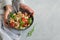 Top view of woman hand holding ready to eat beans salad, healthy protein rich meal with fresh arugula leaves