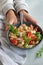 Top view of woman hand holding ready to eat beans salad, healthy protein rich meal with fresh arugula leaves