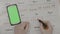 Top view of woman hands crossing on calendar days planning birth prevention with green screen smartphone tracking period -