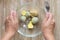 Top view of woman hands holding fork to crush boiled yolks and mustard in the glass bowl to make flavoring for okroshka