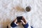 Top view of woman hands holding a smart phone over white background. Cup of coffee besides. Lifestyles. Indoors.