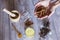 Top view of woman hands with ingredients on table, wooden mortar, yellow turmeric, clove and green natural leaves. Close up,