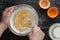 Top view of woman hands mixing with whisk yolks, starch and sugar in bowl for making custard cream on the black background