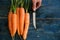 Top view of woman hands peeling fresh raw carots on rustic blue table