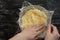 Top view of woman hands placing piece of plastic wrap directly over surface of custard cream on the black background
