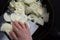 Top view of woman hands putting cut onion into pan to fry or caramelize on the black background
