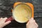 Top view of woman hands stirring hot thick mix of yolks, starch, sugar and milk making custard cream on the black background