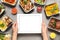 Top view of woman holding tablet over grey table with lunchboxes. Healthy food delivery