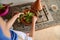 Top view of a woman housewife putting fresh green beans on vegetables, steaming in tagine clay pot