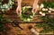 Top view of woman making wreath with beautiful flowers at wooden table, closeup