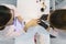 Top view, woman manicurist doing manicure, painting nails, using ultraviolet lamp for fixing gel nail polish. Nail and hand care