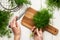 Top view of a woman`s hand, fresh dill on a cutting board, knife and bunches of dill on a white wooden table. Fresh greens, seaso