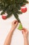 Top view on woman`s hands holding homemade Christmas tree cookie on white wooden background with spruce branches