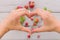 Top view on woman`s hands making heart on fresh organic strawberries grey table background. Healthy food concept