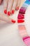 Top view woman selects yellow color shellac nail polish.Nail technician shows the color palette of nail services in beauty salon.