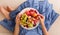 Top view on woman sitting cozy on the couch and enjoying delicious summer fruit and berries. Girl holding white plate