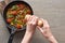 Top view of woman sprinkling pepper on omelet on frying pan.