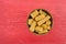 Top view of a wood bowl filled with canned organic baby corn offset on a red painted background