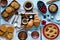 Top view of a wood table full of cakes, fruits, coffee, biscuits
