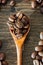 Top view of wood teaspoon filled with coffee beans rounded with coffee seeds over the woodeen background