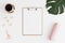 Top view of a wooden clipboard mockup with  workspace accessories, coffee and a monstera leaf on a white table