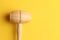 Top view of a wooden kitchen mallet on a yellow background