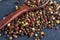 Top view of a wooden spoon full of allspice seeds on dark background, shallow depth of field, front focus